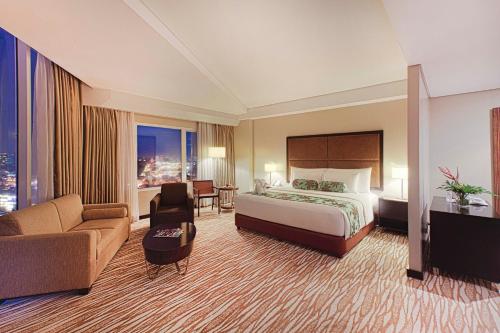 duży pokój hotelowy z łóżkiem i kanapą w obiekcie Acacia Hotel Manila w mieście Manila