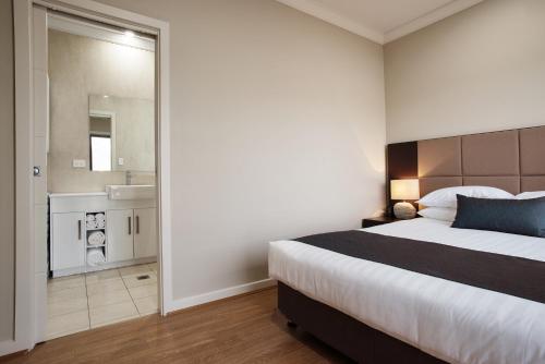 a bedroom with a large bed and a bathroom at Renmark Holiday Apartments in Renmark