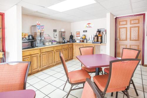 a restaurant with a table and chairs and a kitchen at Super 8 by Wyndham Clinton in Clinton
