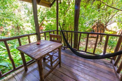 a wooden porch with a hammock on a deck at Khao Sok Riverside Cottages in Khao Sok