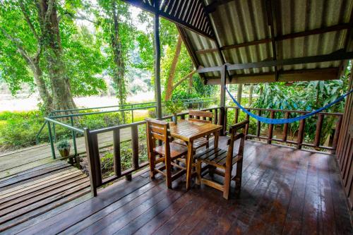 a porch with a wooden table and chairs on it at Khao Sok Riverside Cottages in Khao Sok