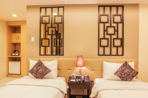 two beds in a room with two mirrors at The Exchange Regency Residence Hotel Managed by HII in Manila