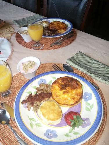 a table with two plates of breakfast food and orange juice at A Hyde Away Inn B&B in Tok