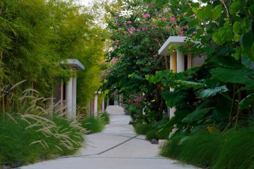 un sendero ajardinado con flores rosas y árboles en Vinila Villas by Nakula, en Nusa Dua