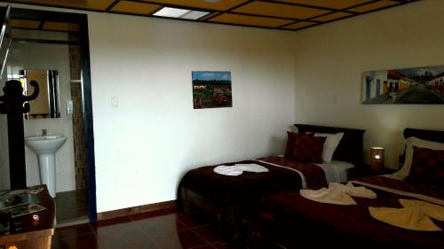 a bedroom with two beds and a sink and a mirror at Finca Cardonales in Salento