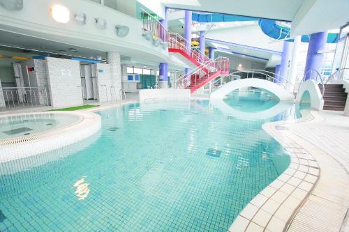 a large swimming pool in a large building with a swimming pool at Sagayamato Onsen Hotel Amandi in Saga