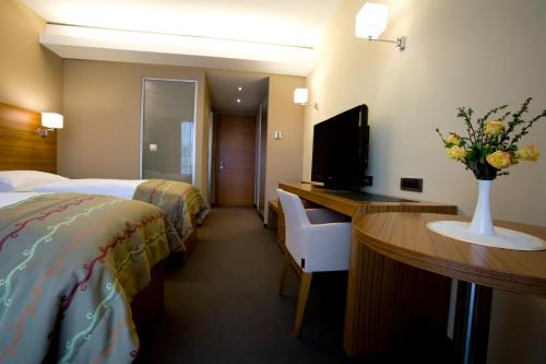 a hotel room with two beds and a desk with a television at Bohinj Eco Hotel in Bohinj