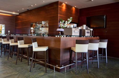 a bar in a restaurant with wooden walls and white stools at Bohinj Eco Hotel in Bohinj