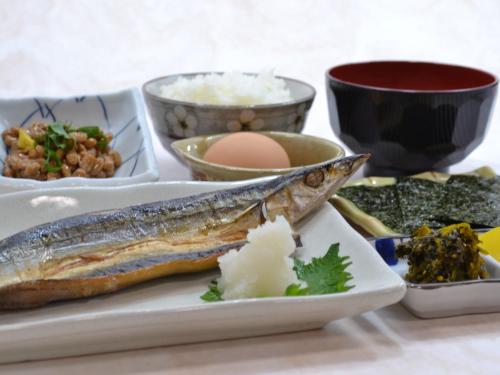 a plate of food with a fish on a table at Onsenminshuku Kosakaya in Nachikatsuura