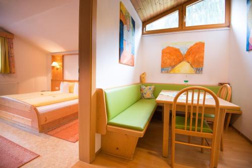 a bedroom with a green couch and a table and a bed at Apart-Pension Wasserfall in Neustift im Stubaital
