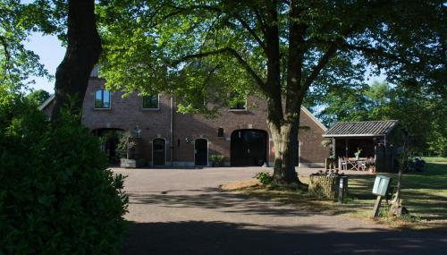 a large brick building with a tree and a house at B&B Erve de Bosch in Benteloo