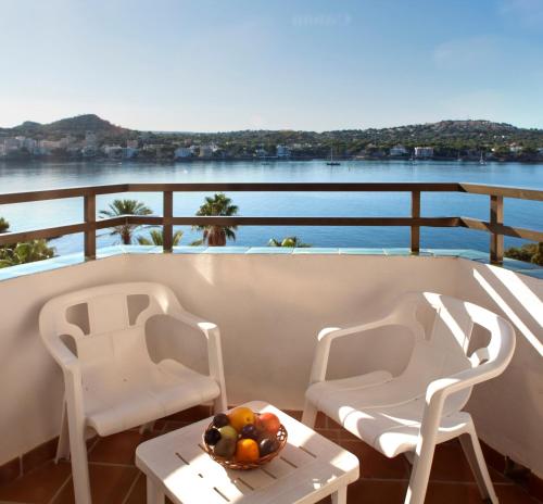 two chairs and a table with a bowl of fruit on a balcony at TRH Jardín Del Mar in Santa Ponsa
