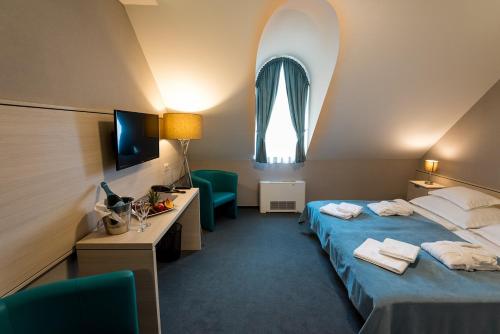 a hotel room with a bed and a desk and a window at Hotel Kamilla in Balmazújváros