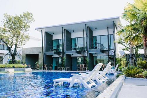 a house with a swimming pool and white lounge chairs at Sp3 Hotel in Ban Na