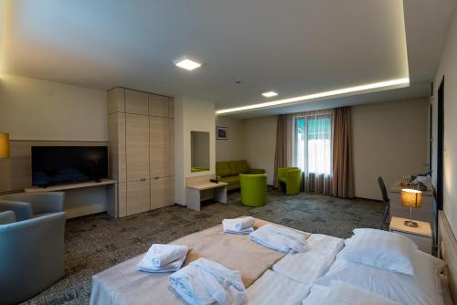 a hotel room with a large bed and a living room at Hotel Kamilla in Balmazújváros