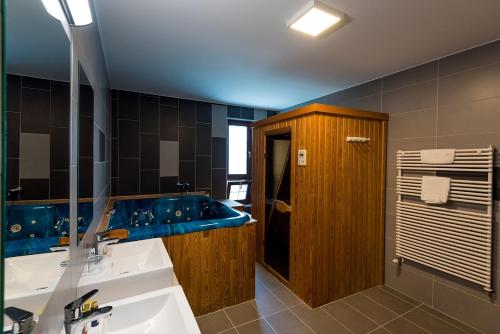 a bathroom with a sink and a blue tub at Hotel Kamilla in Balmazújváros