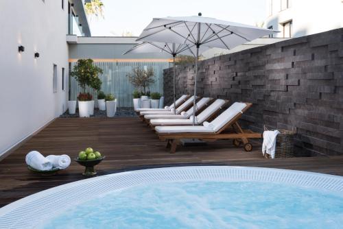 a patio with a bunch of lounge chairs and an umbrella at U Boutique Kinneret by the Sea of Galilee in Tiberias