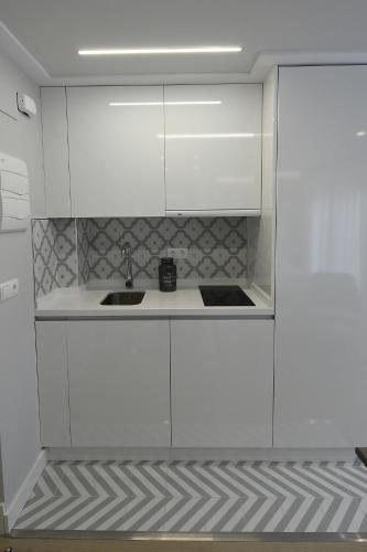 a kitchen with white cabinets and a sink at LEÓN SUITE Urban Studios in León