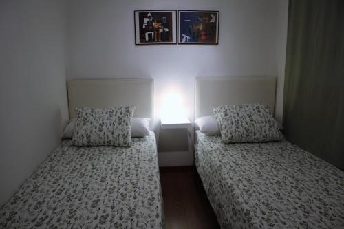 バレンシアにあるApartamento Serranos CMのベッド2台(壁にライト付)が備わるベッドルーム1室