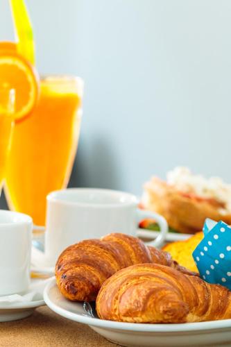 Ein Teller mit zwei Croissants auf einem Tisch mit Orangensaft in der Unterkunft Christina Beach Hotel in Chania