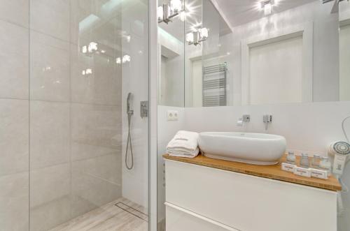 biała łazienka z umywalką i prysznicem w obiekcie Dom & House - Apartamenty Nadmorski Dwór w Gdańsku