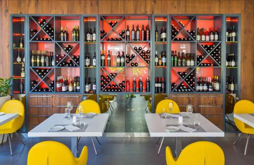 a restaurant with white tables and yellow chairs and a wall of wine bottles at Apartments Mon Amour in Dubrovnik