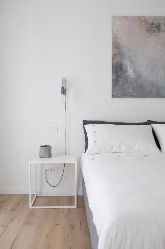 a white bedroom with a bed and a side table at Arco Dei Sogni in Arco