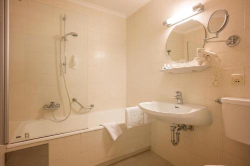 a bathroom with a shower and a sink and a tub at Sporthotel Austria in Sankt Johann in Tirol