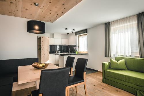 a kitchen and living room with a table and a green couch at Lüch de Costa in Colfosco