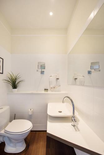 a white bathroom with a toilet and a sink at Hotel Stralsund in Stralsund