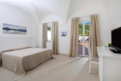 a bedroom with a bed and a desk and a television at Villa Pollio Guest House in Anacapri