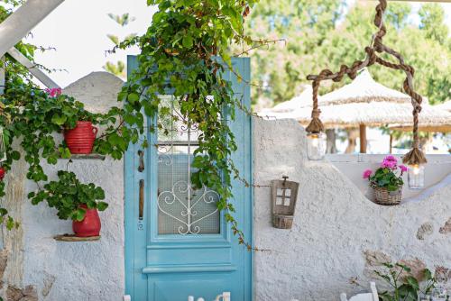 a blue door on a white wall with potted plants at Sonio Beach - Que Bella Collection in Plataniás