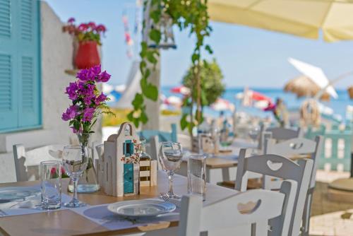 a table with wine glasses and flowers on a beach at Sonio Beach - Que Bella Collection in Plataniás