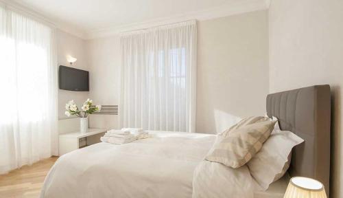 a white bedroom with a large white bed with pillows at Milan Royal Suites - Centro in Milan