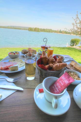 a table with breakfast foods and drinks on a table by the water at Eden Park Hotel Restaurant in Pont-lʼÉvêque