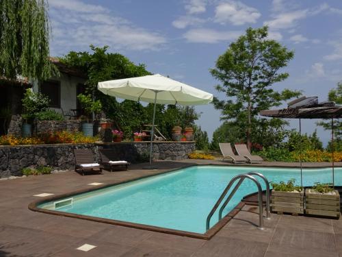 una piscina con sombrilla, sillas y sombrilla en Alberto's Mt.Etna B&B, en Zafferana Etnea