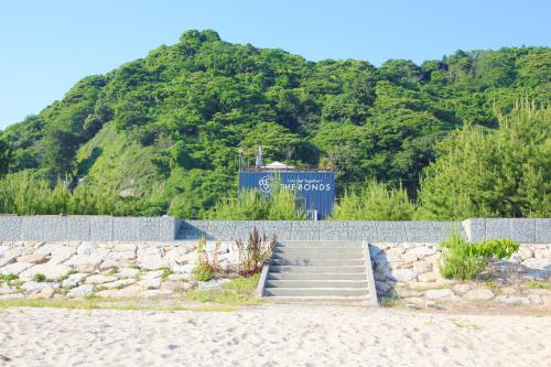 una scalinata su una spiaggia con una montagna di なにもない幸せな島のリトリート宿 THE BONDS Island Stay a Matsuyama