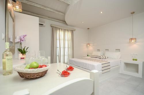 a white room with a bed and a bowl of fruit on a table at Agnadi Hotel in Agia Anna Naxos