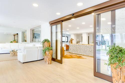 a living room with white furniture and glass doors at Hotel Bellariva in Lido di Jesolo