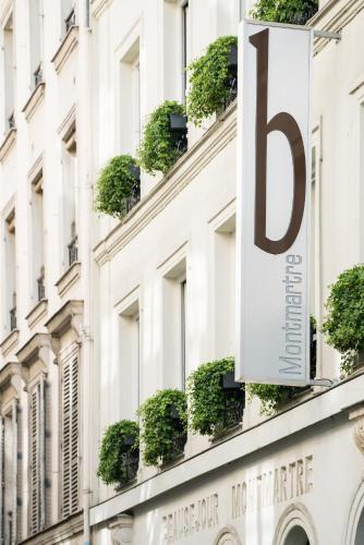 a sign on the side of a building with potted plants at B Montmartre in Paris
