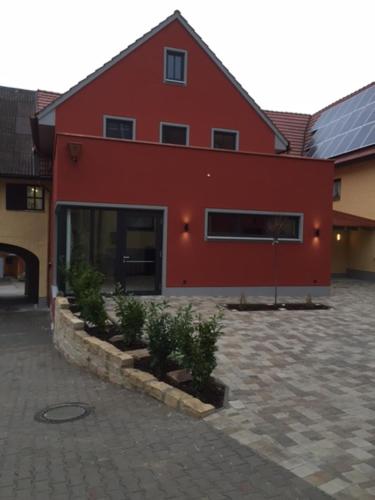 a red building with potted plants in front of it at Hotel-Gasthof Zur Post in Velburg
