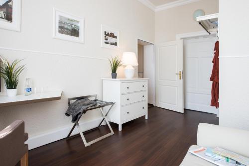 a white bedroom with a white dresser and a desk at Hotel Stralsund in Stralsund