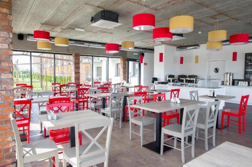 a dining room with tables and red chairs at Siesta in Grzybowo