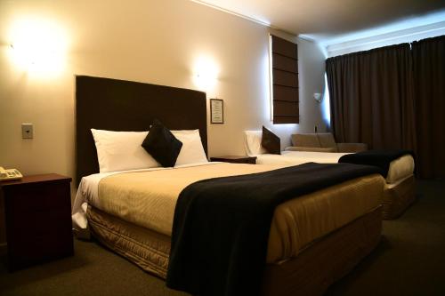 a hotel room with two beds and a couch at City Central Motel Apartments in Christchurch