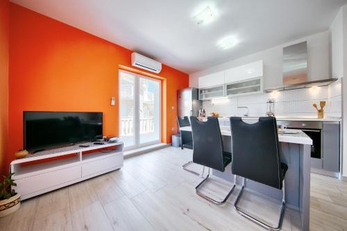 a kitchen with an orange wall and a counter with chairs at Apartments Dalmatino in Rukavac