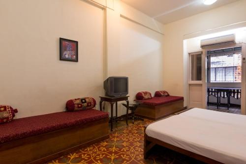 een hotelkamer met 2 bedden en een televisie bij Bed and Breakfast at Colaba in Mumbai