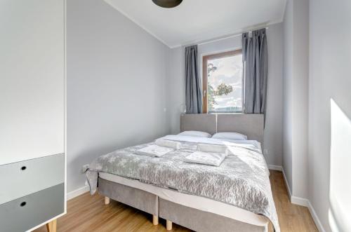 a white bedroom with a bed and a window at Amber Baltic Apartment in Gdańsk