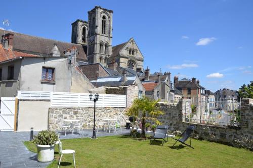 um edifício com um quintal com cadeiras e uma igreja em Le Clos Saint Martin em Laon