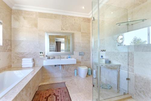 a bathroom with a tub and a sink and a shower at Vetho Villa in Cape Town