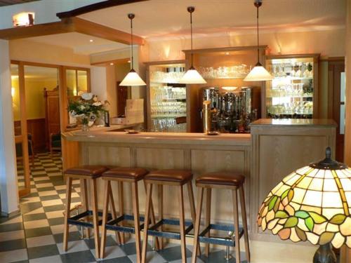 a bar with four stools in a room at Landhaus Silberberg in Winterberg